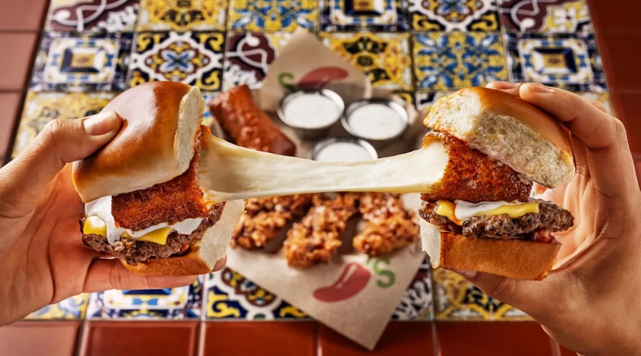 Hands pulling apart two Chili’s cheeseburger sliders with gooey melted cheese stretching between them, served on a colorful tiled table alongside dipping sauces and crispy appetizers.